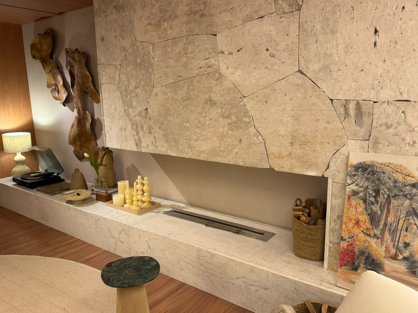 Lareira ecológica linear em bancada de mármore com parede de pedra natural