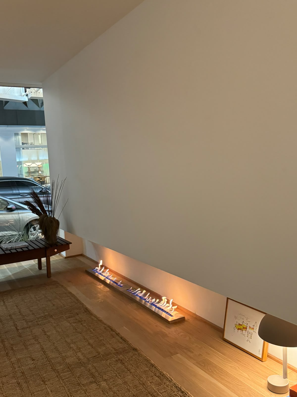 Lareira ecológica linear acesa junto à parede em showroom